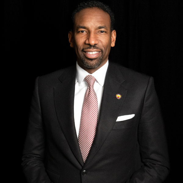 A middle-aged African American man with a goatee, salmon-colored tie, white shirt, black jacket, and white lapel